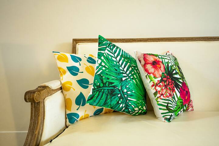 Add a pop of colour to your Goa getaway! These vibrant, tropical-themed cushions adorn comfortable seating, inviting you to relax in style.