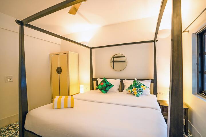 Rest easy in this cosy bedroom at our Goa villa, featuring a charming four-poster bed, tropical accents, and a tranquil ambiance for your peaceful retreat.