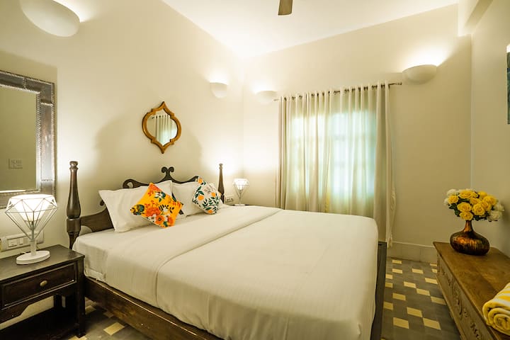 Unwind in this charming bedroom at our Goa villa, featuring a comfortable bed, elegant décor, and a serene ambiance for a restful night's sleep.