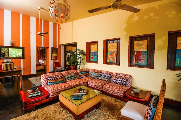 Vibrant & spacious living area in our 5BHK Luxury Villa in Goa. Relax on the colourful sofa, surrounded by eclectic art and stylish décor.