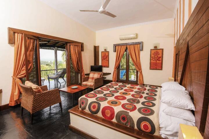 Experience luxury at this 5BHK villa in Goa! This spacious bedroom offers a comfy bed, cosy seating, and a private balcony with stunning views.