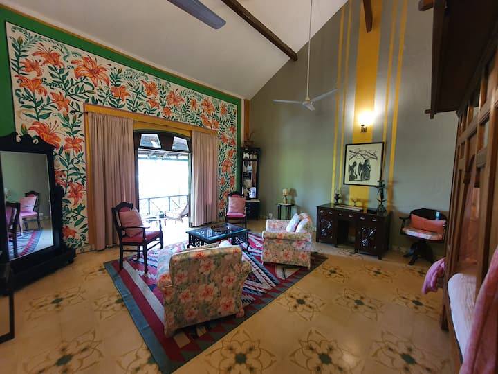 Experience a blend of vintage charm and modern comfort in this spacious living room. The vibrant floral mural and high ceilings open to a balcony, making it the perfect spot to unwind at our 6BHK Luxury Villa in Goa.
