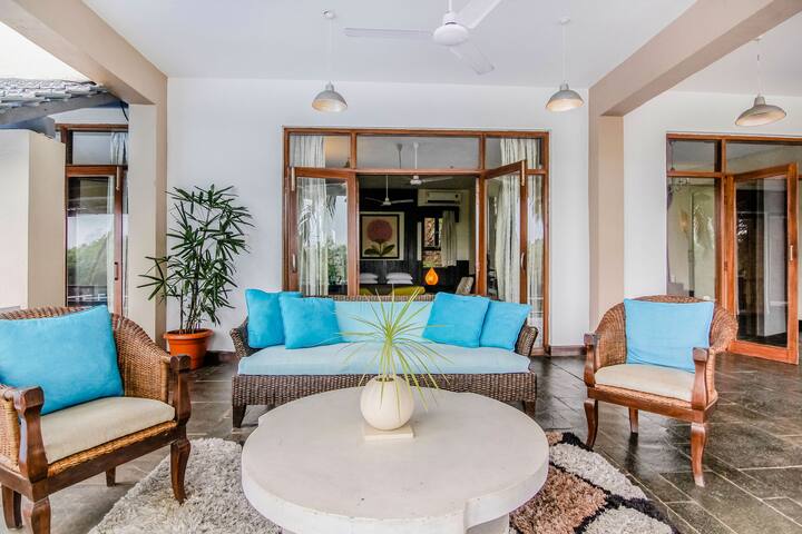 Relax in vibrant luxury at this 7BHK villa in Goa! This spacious living area features cosy seating, artistic touches, and ample natural light.