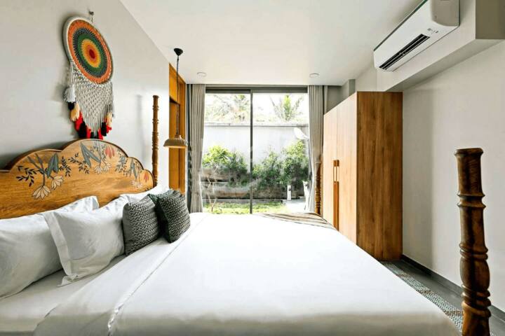 Wake up to tranquillity in this charming bedroom at our Goa villa, featuring a unique hand-painted bed and lush garden views for a serene Goan escape.