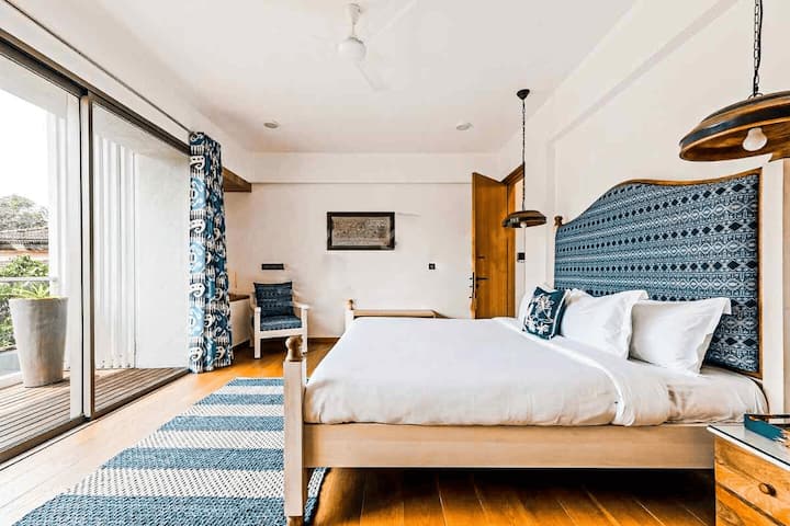 This bright and airy bedroom in our Goa villa offers a comfy king bed, stylish blue accents, and a private balcony for relaxing.