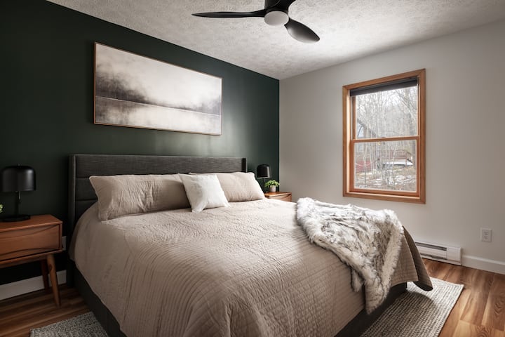 ห้องนอน 3 มีเตียงขนาดคิงไซส์โต๊ะข้างเตียง 2 ตัวพัดลมเพดานพื้นที่กว้างขวางที่สุดและวิวด้านหลังของที่พัก 