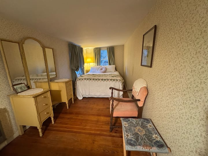 Kvetinová izba na poschodí má manželskú posteľ s kvetinovou posteľnou bielizňou a starožitným nábytkom, ktorá vytvára útulnú vintage atmosféru. Užite si prirodzené svetlo a ľahký prístup k plnej kúpeľni, ktorá ponúka dokonalú kombináciu pohodlia a šarmu pre pokojný pobyt.