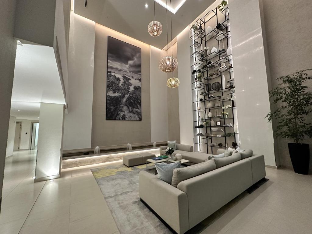 A spacious lobby area is presented with modern decor and neutral tones. A large photographic artwork adorns the wall, adding visual interest. A sleek shelving unit holds decorative items, while a plush sectional sofa invites relaxation. Soft lighting and natural elements enhance the inviting space.
