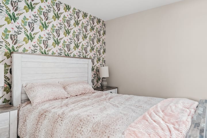 Bedroom with a charming floral accent wall and plush bedding.