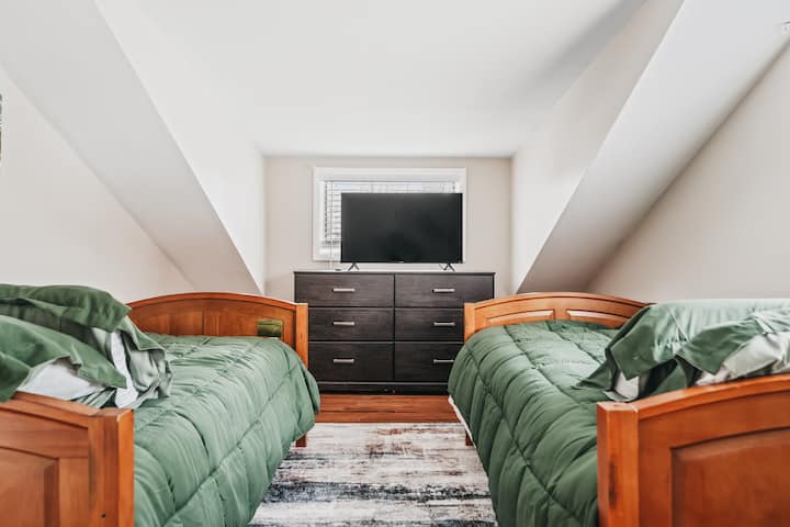 Charming attic bedroom with twin beds, cozy green bedding, and a TV!