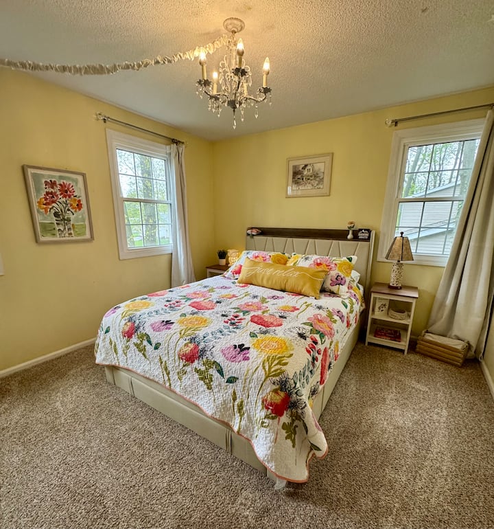 The spring-themed bedroom features a vibrant color palette and a comfortable queen-sized bed, creating a bright and refreshing atmosphere.