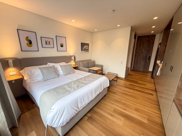 חדר עם מיטת קווין סייז, וילון ושחור, טלוויזיה חכמה ושני שידות לילה.