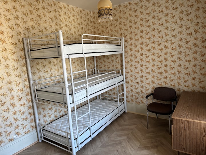 habitación con triple litera y un lavabo y un escritorio