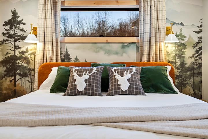 ¡Relájate en el dormitorio principal, con una lujosa cama tamaño king y un mural en la pared del bosque!