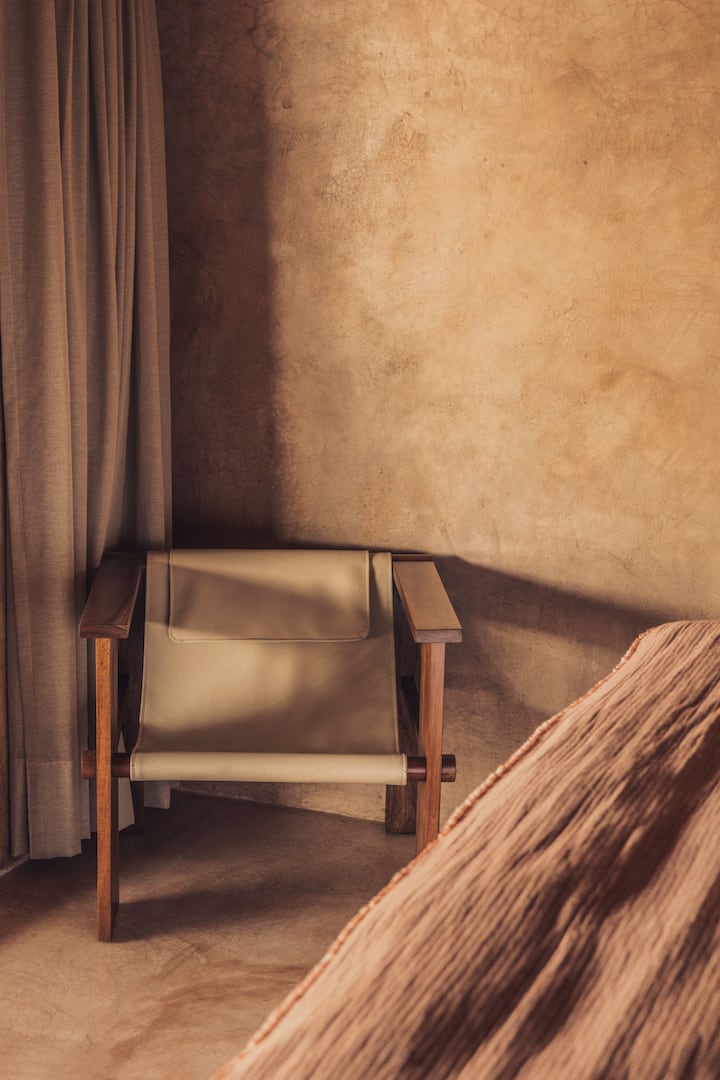 - Silla de lectura minimalista en tonos naturales cálidos   - La luz del sol y las sombras crean texturas relajantes   - Un rincón acogedor para una reflexión tranquila  