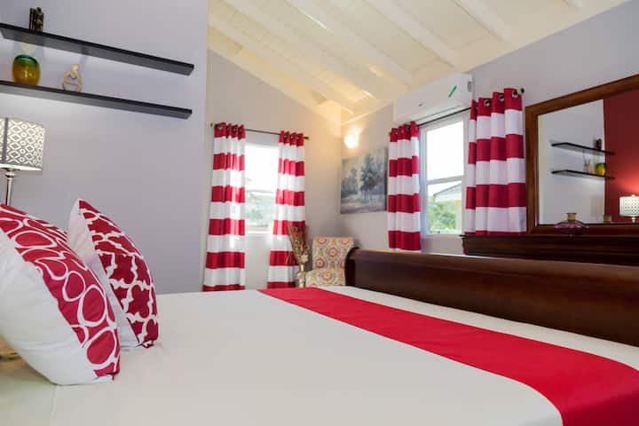 Dormitorio espacioso y bien iluminado con una cama tamaño king, aire acondicionado y ventilador de techo.