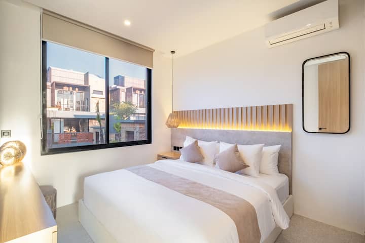 Светла и уютна спалня с панорамна гледка към зелени площи и акценти от естествена дървесина.