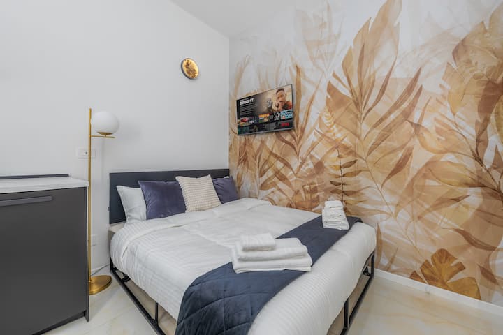 Espace nuit raffiné avec lit double confortable, oreillers moelleux, Smart TV et un magnifique papier peint élégant.