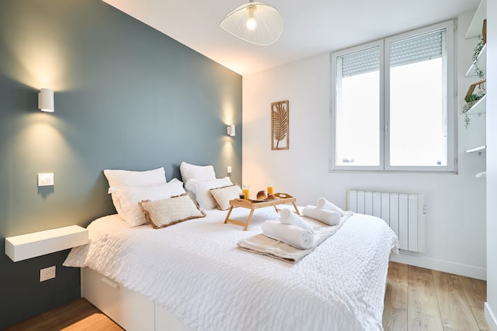 غرفة مشرقة وأنيقة مع سرير كبير من الكتان الأبيض المزخرف ووسائد طبيعية وجدار أخضر عميق. أضواء حائط لجو مريح. جو مهدئ.