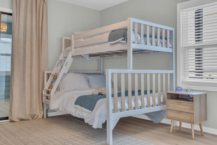 Grande chambre du milieu avec lits jumeaux sur un lit double. Peut dormir jusqu'à 3 personnes ici. Des lits pour bébé portatifs sont disponibles dans le placard. Machine à sons sur la table de chevet.