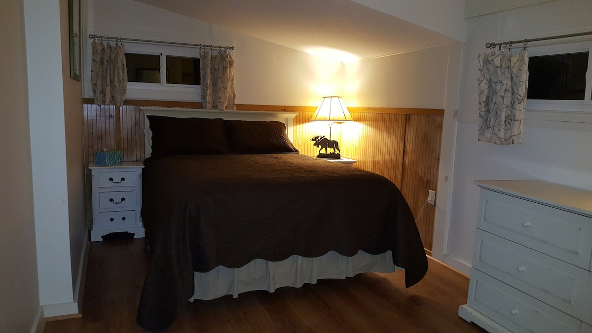 Dormitorio con cama tamaño queen y vistas o árboles circundantes.