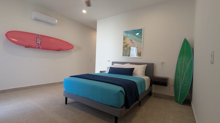 Dormitorio principal con mesitas de noche, armarios grandes y tocador de maquillaje que conducen al baño principal privado y puertas corredizas de vidrio hacia el patio trasero privado.