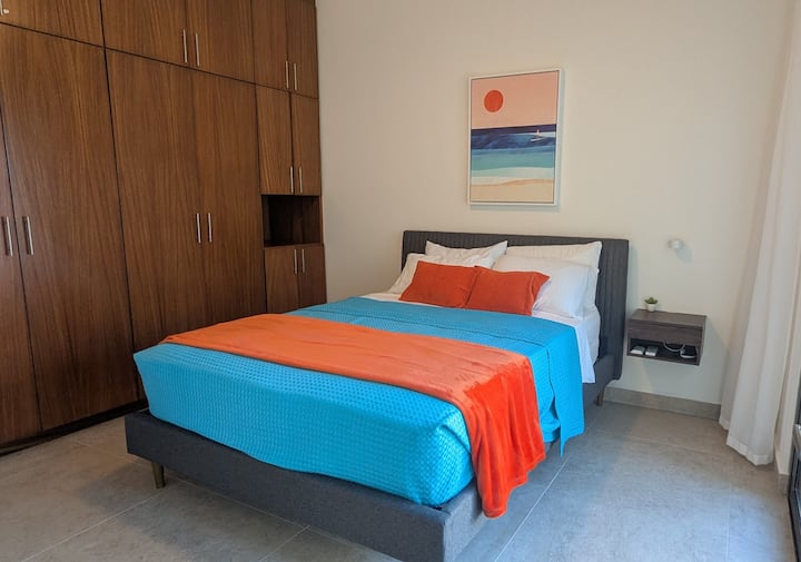 Segundo dormitorio con mesita de noche, armario grande y puerta corrediza de vidrio al patio trasero.