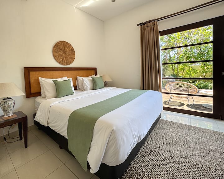 Habitación tropical luminosa con cama tamaño queen y vista al jardín en nuestra tranquila villa de Bali.