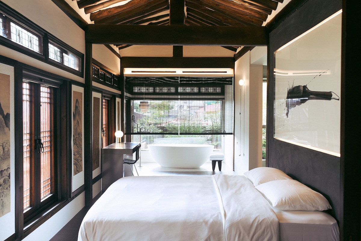 Master room view.
1 LK size bed is available.
There is a sink, shower, and toilet beyond the wall behind the bed.
As you can see in the picture, there is a bathtub with a garden view. 
Beyond the garden, you can also see Namsan Tower, a symbol of Seoul. 
You can enjoy a half-body bath while viewing Namsan Tower.