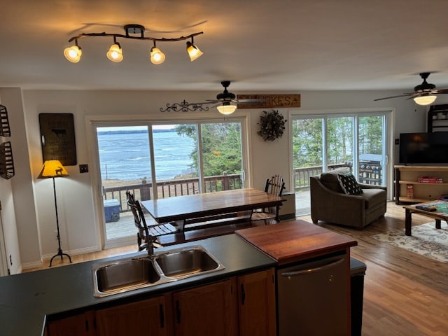 An open-concept living and dining area is visible, featuring a large table that seats eight. Windows span the wall, providing views of Moosehead Lake. A comfortable seating area is present with a couch and coffee table, while warm lighting illuminates the space.