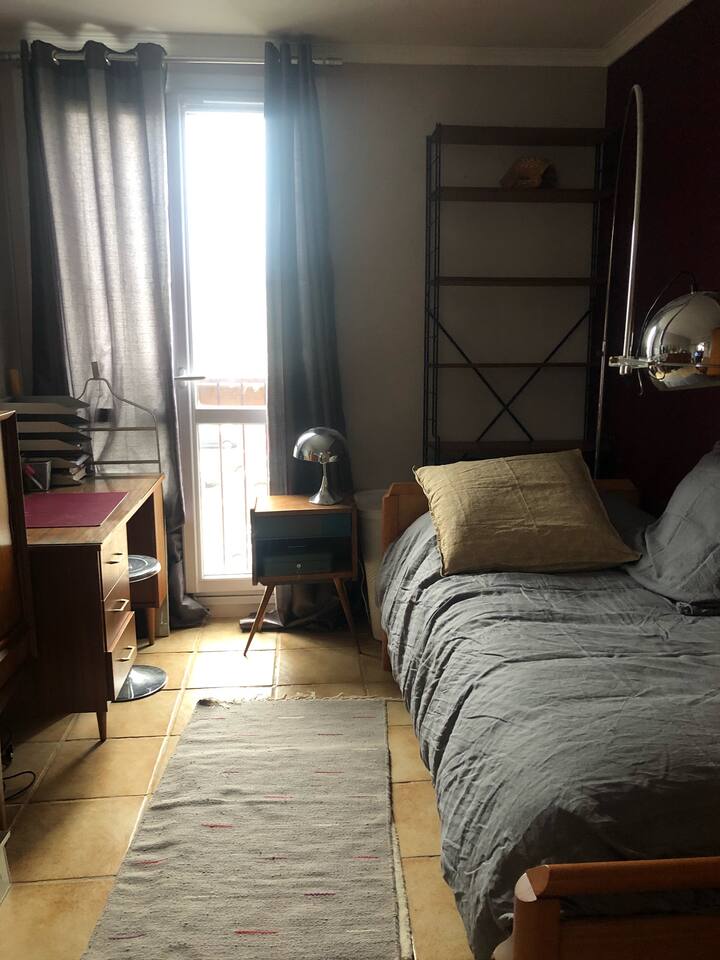 Единечна спална соба опремена со кревет, ноќна масичка, библиотека, биро, корпа за валкани алишта, стол, фотелја и гардероба со висечки простор и полици.