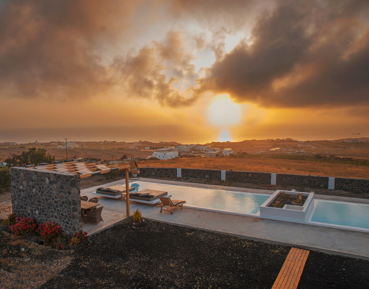 A tranquil scene captures the outdoor area featuring a seasonal swimming pool and sun loungers. The sun rises on the horizon, casting a warm glow over the landscape. Natural stone walls complement the swimming pool, and flowers enhance the serene environment.