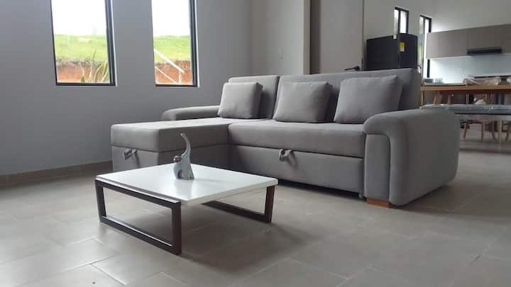 Пространа соба со кауч на спуштање во која 3 лица можат удобно да спијат.