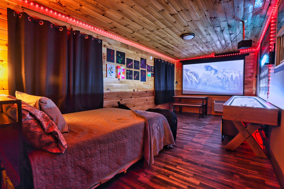 Our back bedroom, game room, and movie theater combo has a full bed with a twin trundle, board games, a shuffleboard table, surround sound, a projector, and bean bag chairs. It has LED's and black lights for fun game nights too!