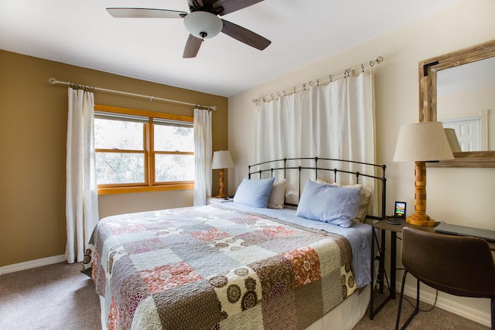 Svijetla spavaća soba s velikim bračnim krevetom, radnim prostorom i pogledom na šumu