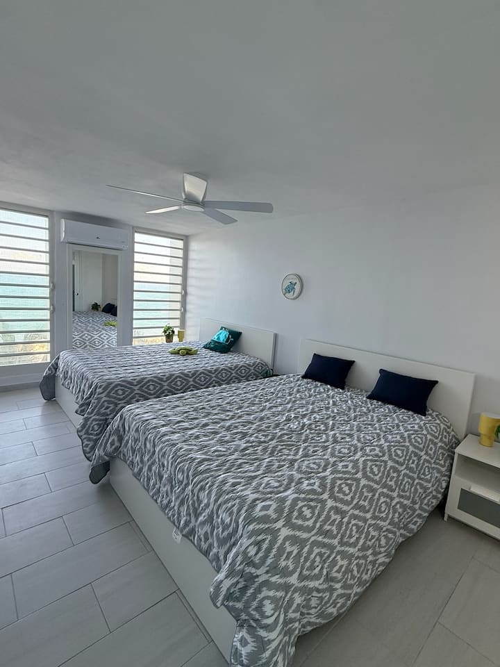 La habitación doble tiene dos camas de colchón de espuma viscoelástica tamaño queen, mesitas de noche y espejo. Hay unidades de aire acondicionado y ventiladores de techo en todos los dormitorios y espacios habitables.