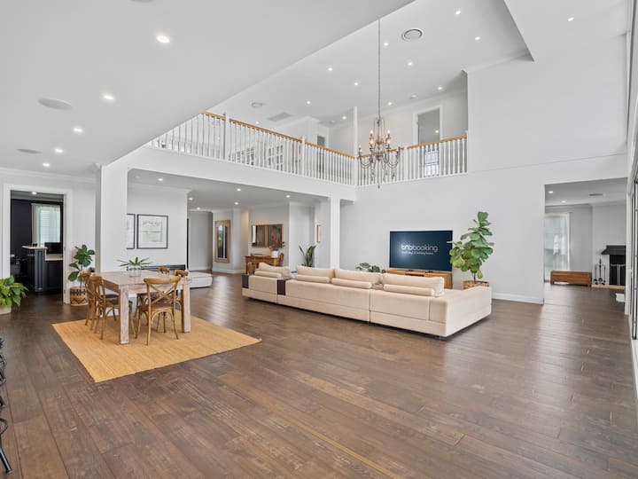 Soggiorno open space con divano letto, tavolo da pranzo e sedie, smart TV da 80 pollici e accesso diretto all'area piscina