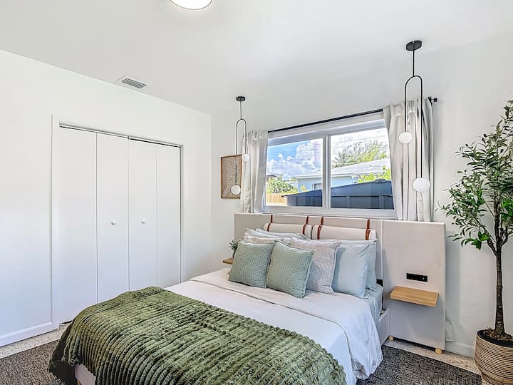 Dormitorio de invitados con televisor inteligente de 55 pulgadas, cama tamaño queen y escritorio y silla.