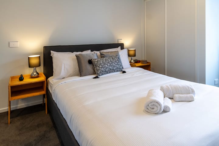 Lujosa cama tamaño queen con ropa de cama cómoda y sábanas de hotel de 5 estrellas.