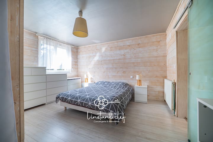 Chambre épurée et lumineuse – Ambiance naturelle avec mur en bois clair et lumière douce pour un réveil tout en douceur.