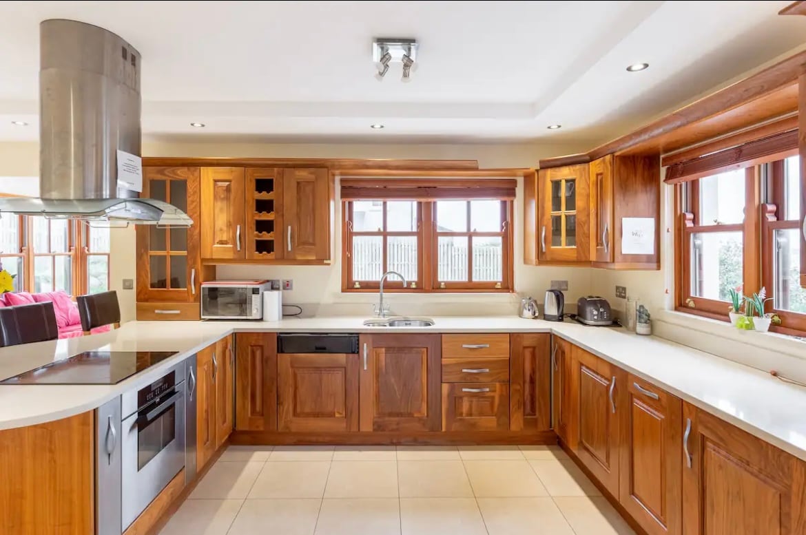 The kitchen features wooden cabinetry and modern appliances, including an oven, microwave, and dishwasher. A large window provides natural light, while ample counter space is available for food preparation. The area is designed for functionality and comfort.