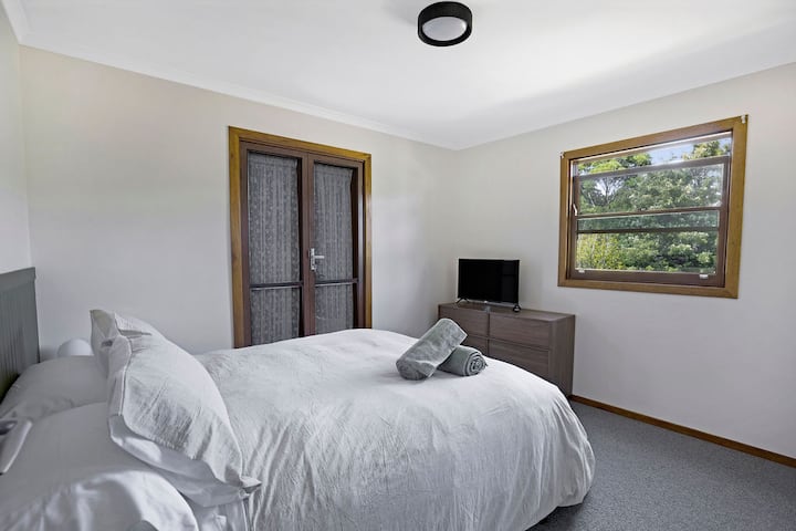 Habitación privada con cama tamaño queen, persianas romanas, bata incorporada, TV inteligente y acceso al baño por el balcón