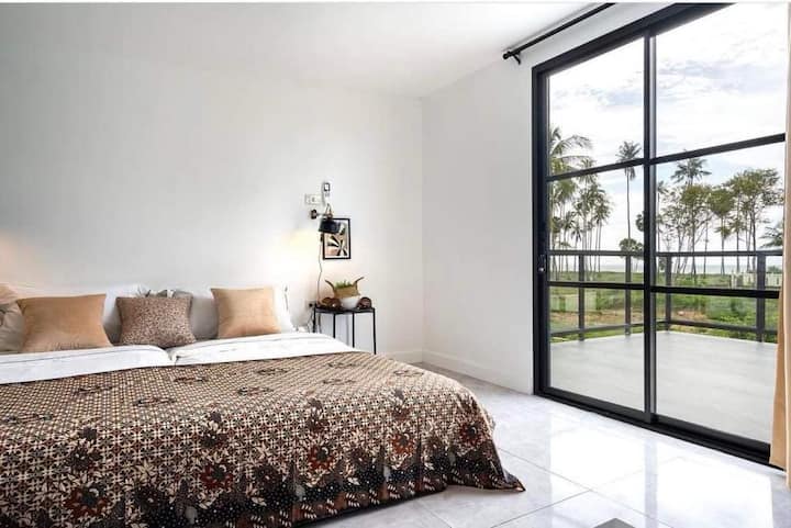 חדר שינה בקומה השנייה עם יציאה למרפסת גג ונוף לים.