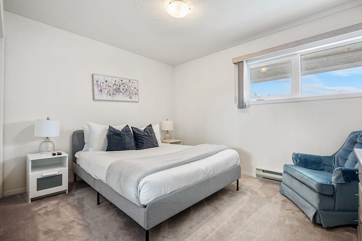 Chumba cha pili cha kulala kilicho na kitanda aina ya queen, Televisheni mahiri, kabati na vivuli vinavyofanya chumba kiwe na giza.