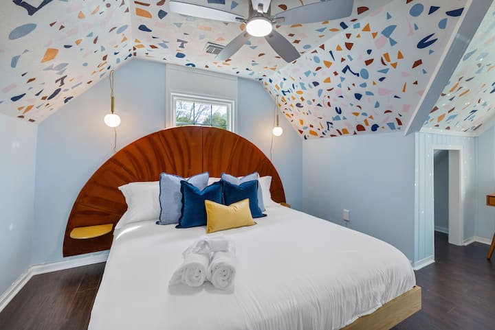 Sleep under the stars (or terrazzo)! This one-of-a-kind king bedroom features a bold arched headboard, playful ceiling design, hanging globe lights, and a 55-inch Smart TV. It’s cozy, creative, and full of personality.