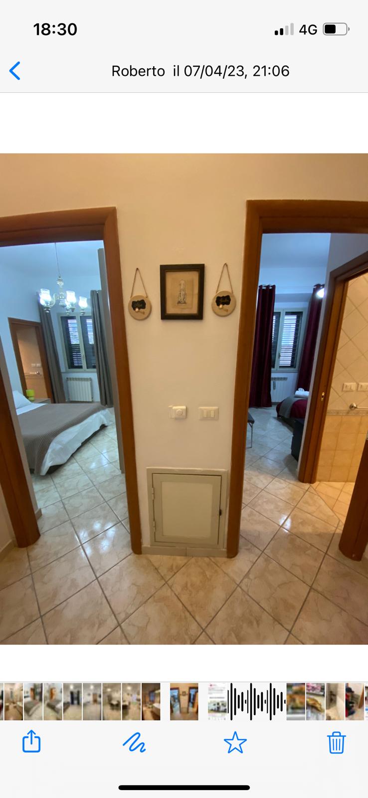 A hallway is visible, featuring two open doorways that lead to separate rooms. Soft lighting creates a welcoming ambiance. The floor is tiled in warm tones, and a small wall-mounted artwork enhances the decor. An access panel is discreetly positioned along the wall.