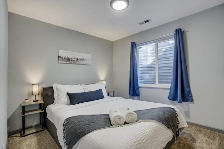 Este sereno dormitorio gris en el sótano cuenta con una acogedora cama tamaño queen y un espacioso armario con muchas perchas, perfecto para estancias prolongadas o huéspedes a los que les gusta mantenerse organizados.