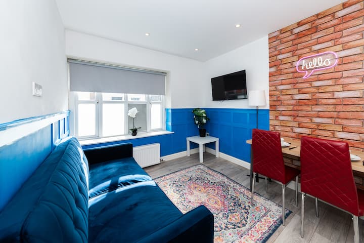 Espacio luminoso y elegante con vibrantes detalles azules, un acogedor sofá, comedor y luz natural.