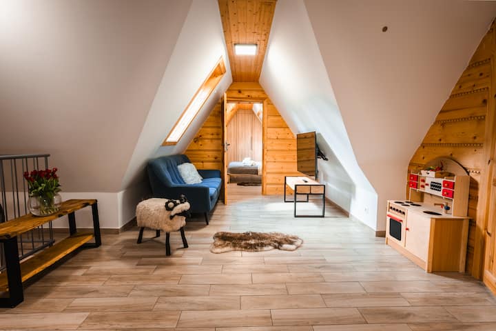 غرفة معيشة مع سرير أريكة ومنطقة للعب الأطفال وتلفزيون وأريكة. 