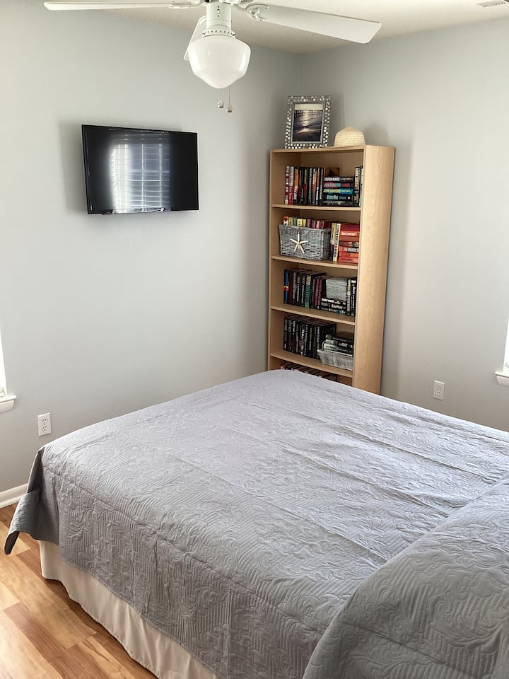 Queen ‑ ის საწოლსა და კედელზე მიმაგრებული ტელევიზორი 1 საძინებელში და კარგი პლაჟია.